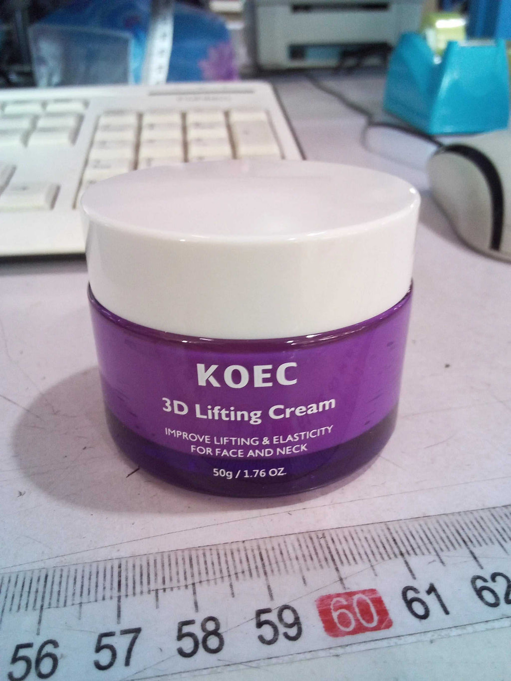 White computer keyboard and blue pen on a desk, with the KOEC 3D Lifting Cream jar in the foreground